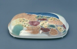 河合誓徳《 彩 》1990

河合誓徳は1964年頃から、制作の主体を陶器から磁器に転換し、陶彫的な作品や、独特の形の筥（＝箱）や壺、陶板等に、花卉や郷土大分の風景を描いた独自の作風を確立しています。この作品には、由布市の塚原高原の秋景が、染付の青色、青磁釉の緑色、釉裏紅の赤色、顔料の黄色など多彩な色で描き出されています。